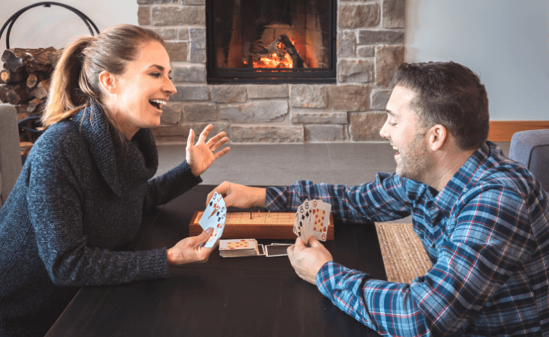 Couple playing with cribbage boards in front of a fireplace